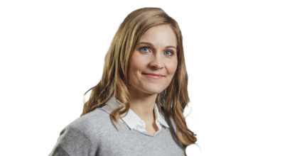 Johanna Kultalahti hymyilee yllään neulepaita kauluspaidan päällä.