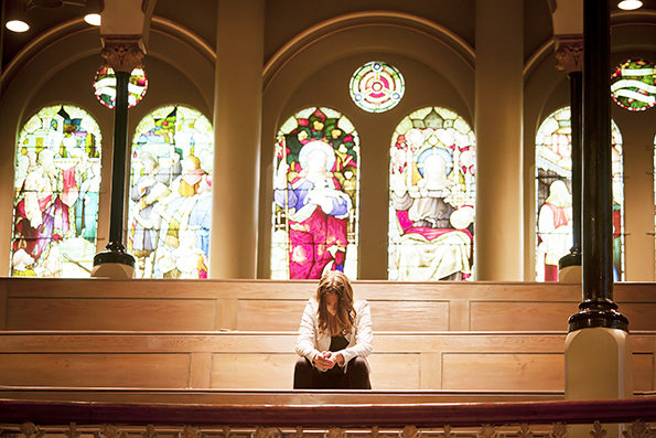 Young woman with head bowed praying in a church