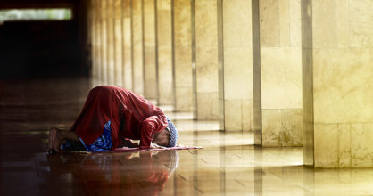 Musliminainen kumartuneena rukoukseen.