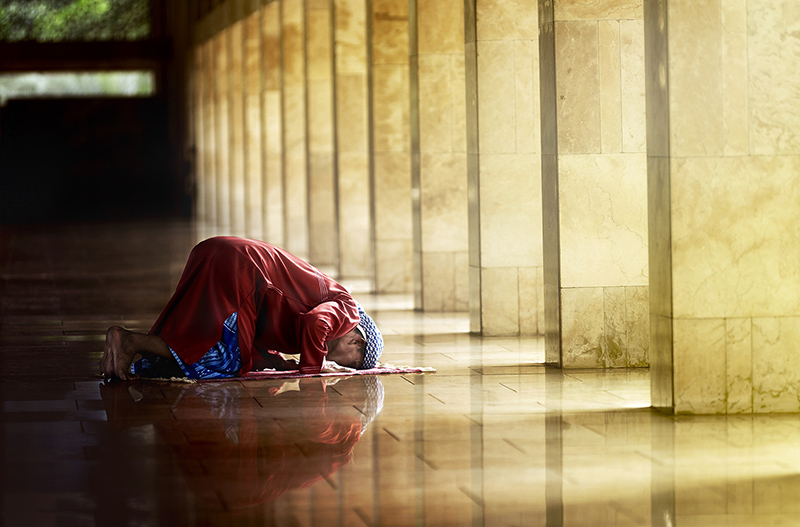 Musliminainen kumartuneena rukoukseen.