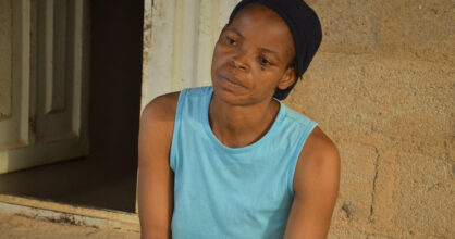 Turkoosissa paidassa oleva nainen katselee eteensä surullisen näköisenä