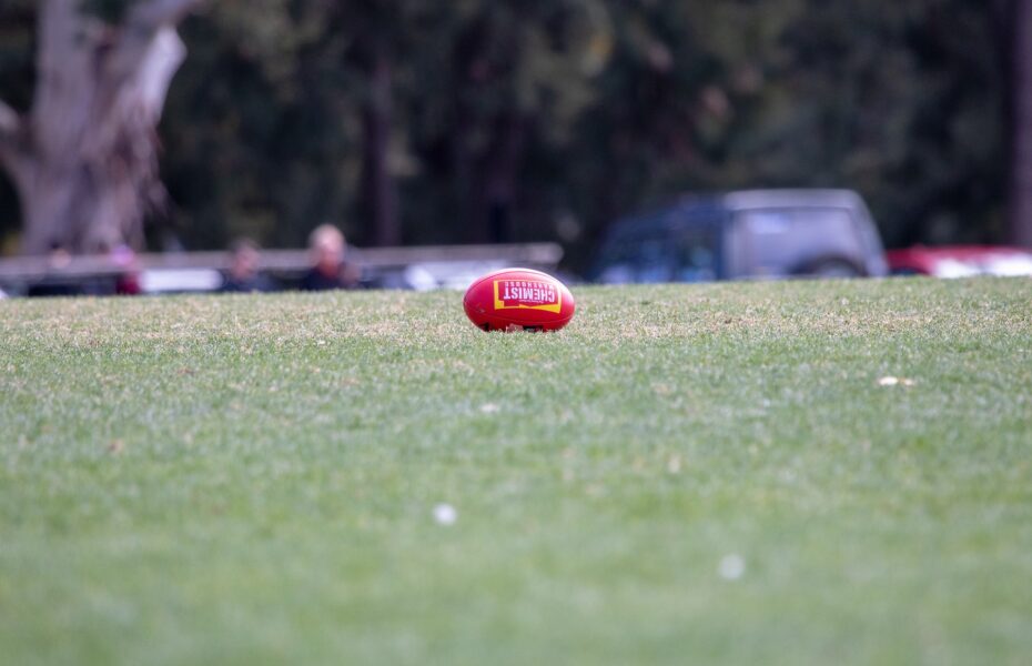 Soikionmuotoinen jalkapallo ruohokentällä.