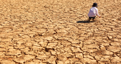 Lapsi on kyykistynyt paikassa, jossa maa halkeilee kuivuuden takia.