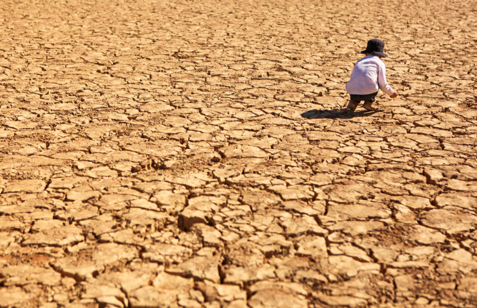 Lapsi on kyykistynyt paikassa, jossa maa halkeilee kuivuuden takia.