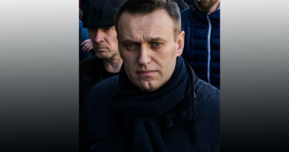 Aleksei Navalnyi väkijoukko takanaan, katsoo vakavailmeisenä eteenpäin.