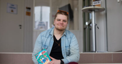 Mies istuu portailla ja pitää käsissään kirjaa.