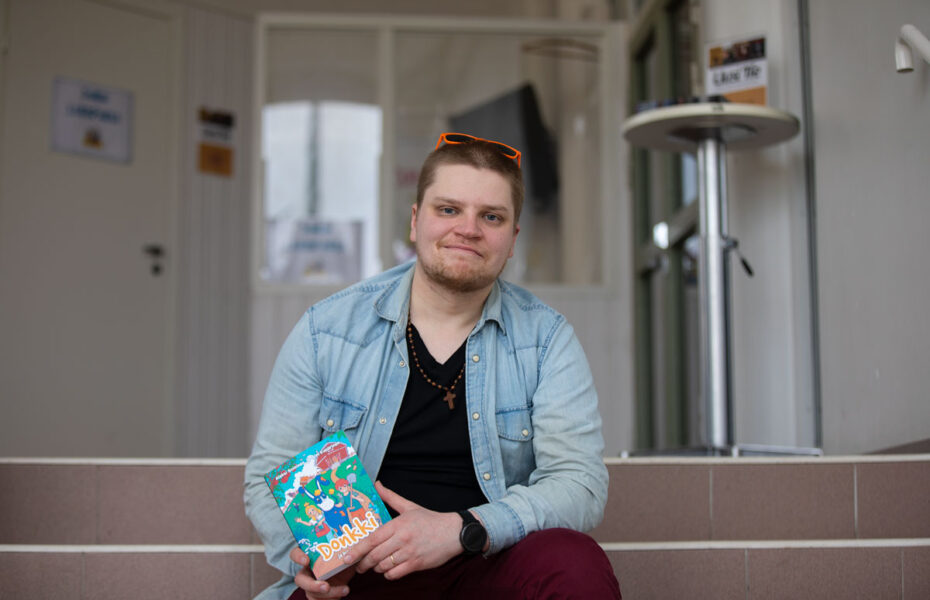 Mies istuu portailla ja pitää käsissään kirjaa.