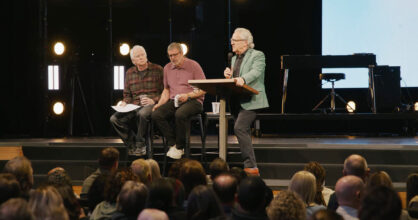 Lavalla istuu kolme miestä pöydän ääressä.