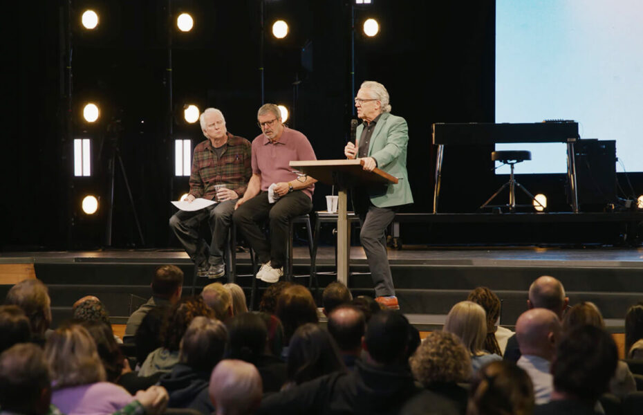 Lavalla istuu kolme miestä pöydän ääressä.