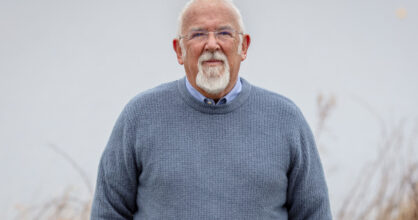 Clive Johnstonilla on silmälasit ja harmaantuneet hiukset ja parta.