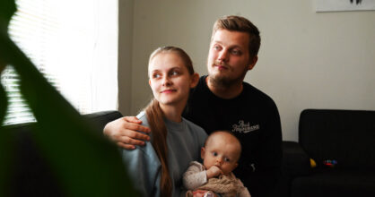 Eeva ja Oliver istuvat sohvalla ja katsovat ikkunasta. Eevan sylissä on vauva.