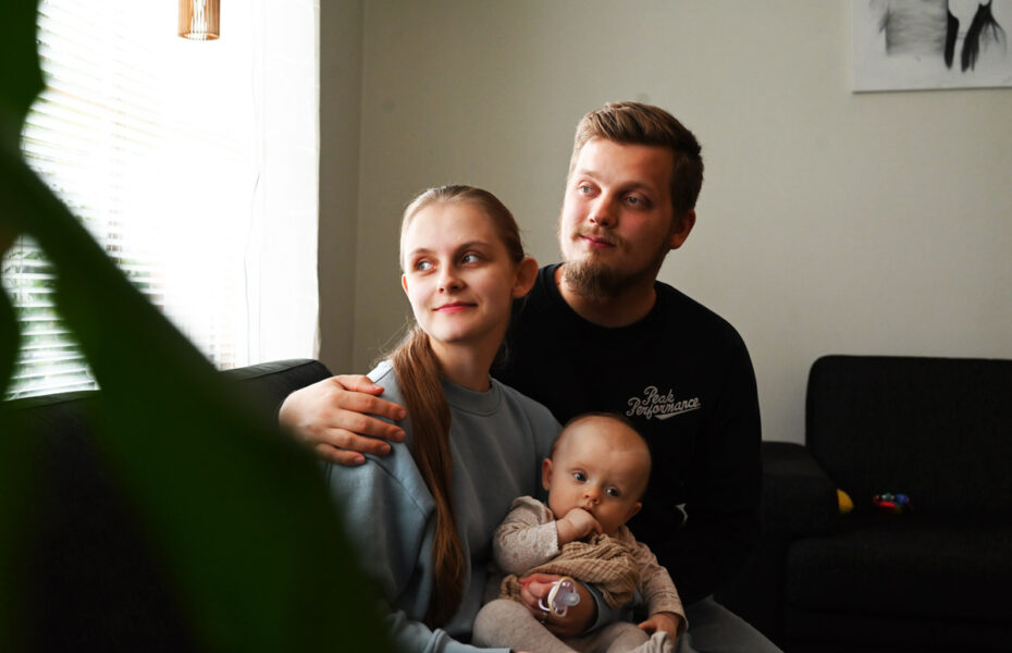 Eeva ja Oliver istuvat sohvalla ja katsovat ikkunasta. Eevan sylissä on vauva.