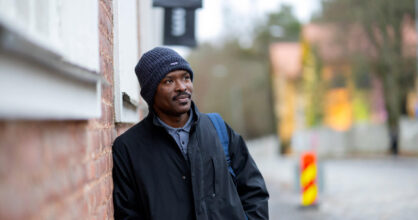 Emmanuel nojaa seinään.