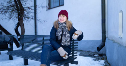 Esteri istuu penkillä. Ympärillä on lunta.