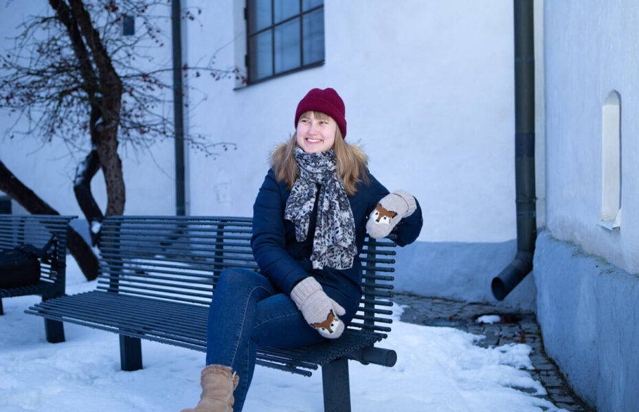 Esteri istuu penkillä. Ympärillä on lunta.