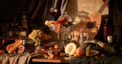 Pöydällä on hedelmiä, hummeri, viiniä ja luuttu. Herkkupöytä kuvaa kuninkaan pitoja.