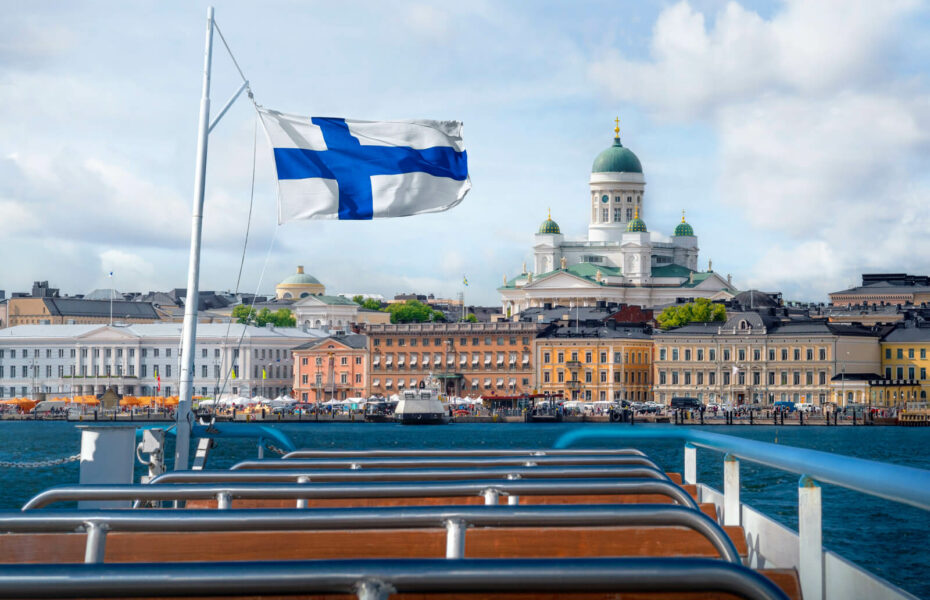 Kuvassa Suomen lippu liehuu ja taustalla näkyy Helsingin Tuomiokirkko.