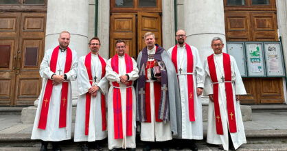 Kirkon portailla seisoo rivissä kuusi pappia.