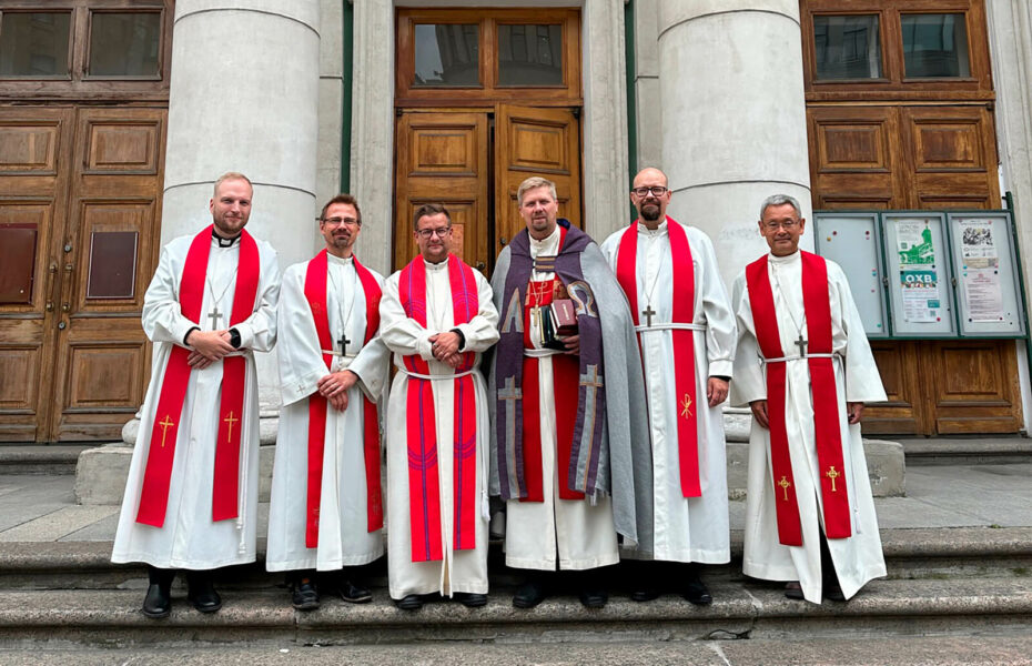 Kirkon portailla seisoo rivissä kuusi pappia.