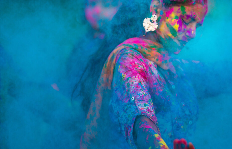 Intialainen nainen, jolla on kasvoissaan ja vaatteissaan värikästä maalia.