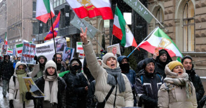 Ihmiset huutavat ja heiluttavat Iranin lippuja kadulla.