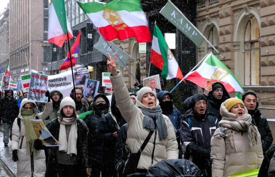 Ihmiset huutavat ja heiluttavat Iranin lippuja kadulla.