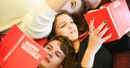 Nuoret makoilevat lattialla ja lukevat Nuorten punainen laulukirja -kirjaa.