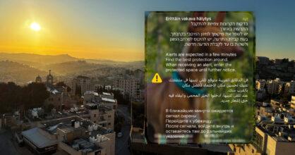 Maisema israelilaisesta kaupungista. Päällä kuvakaappaus kännykästä, jossa varoitetaan Iranin iskuista.