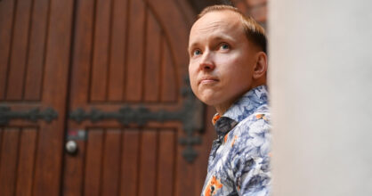 Mies nojaa seinää vasten ja katsoo ylöspäin.