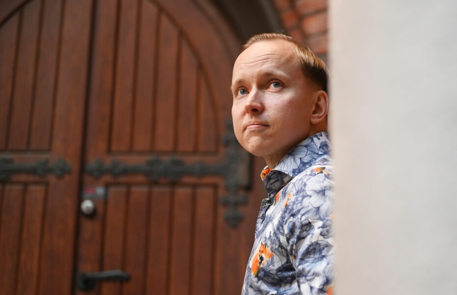 Mies nojaa seinää vasten ja katsoo ylöspäin.