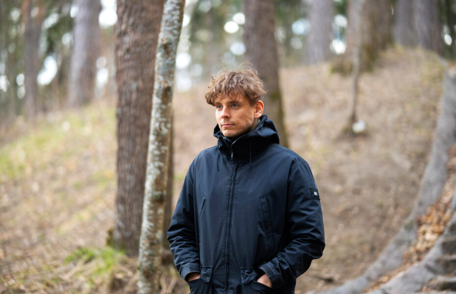 Juhani Tikkanen seisoo puiden rinteellä.