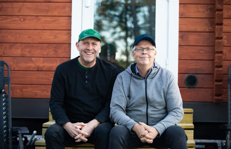 kaksi miestä istuu rappusilla ja hymyilee