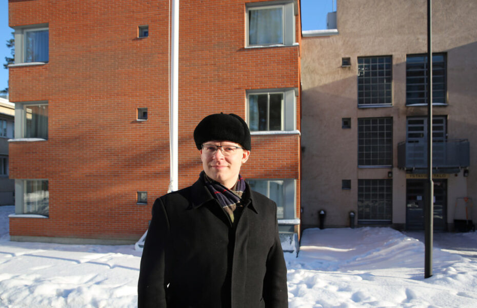 Mies on ulkona. Hänellä on musta lakki ja takki.