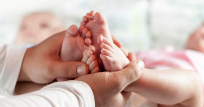 Kädet pitelevät vauvan jalkoja.