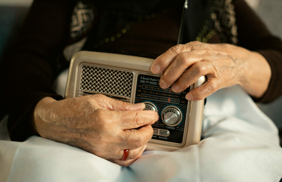 Iäkkään naiset kädet säätävät radiota.
