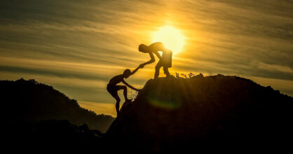 Kaksi poikaa kipeää vuorelle toisiaan auttaen.