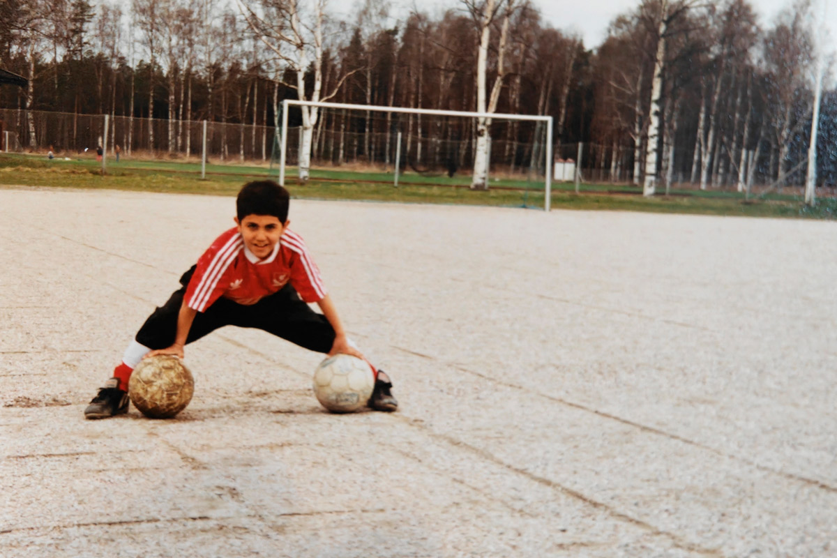 Kamal Jafi pikkupoikana jalkapallokentällä kahden pallon kanssa.