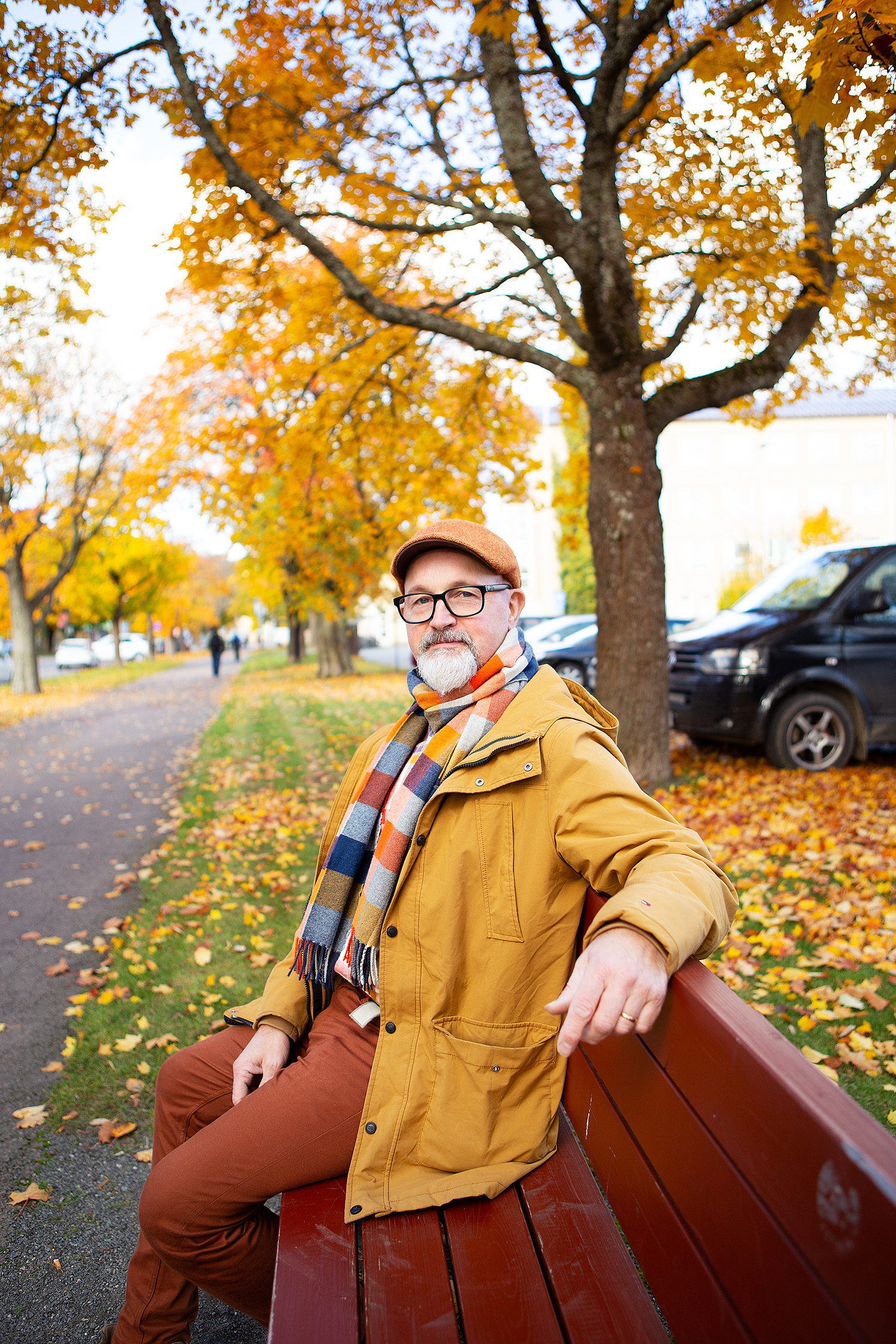 Mies keltaisessa takissaan istuu penkillä.