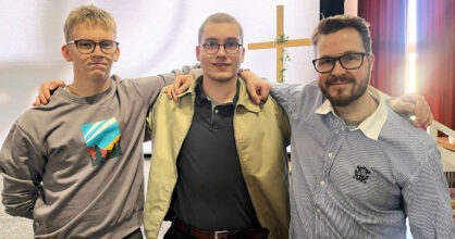 Kolme miestä seisoo rivissä.