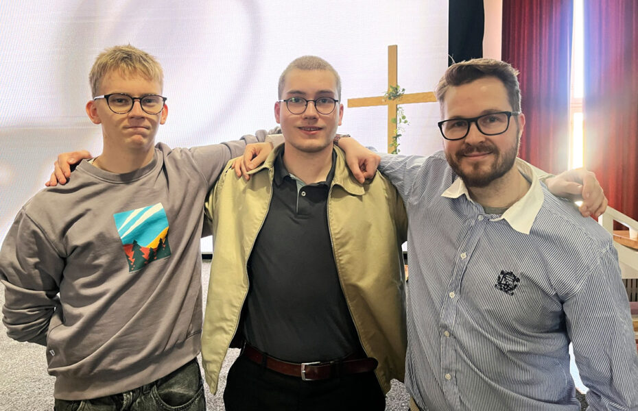 Kolme miestä seisoo rivissä.