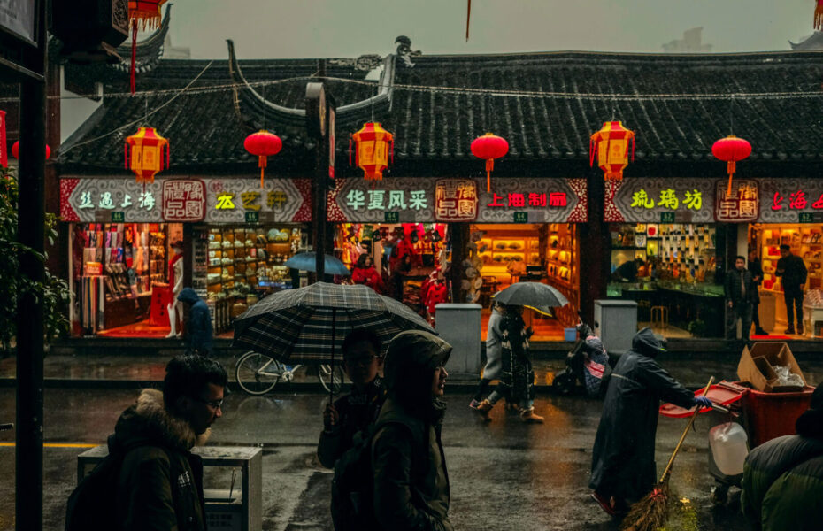 Kiinalainen katu. Ihmiset kantavat sateenvarjoja.