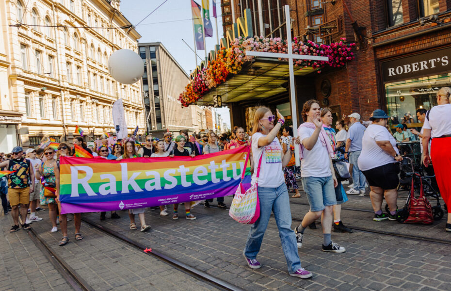 Kulkue kaupungin kadulla. Ihmiset kantavat ristiä ja lakanaa, jossa lukee "rakastettu".