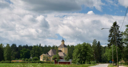 Kirkko pellon reunassa kylätien vieressä.