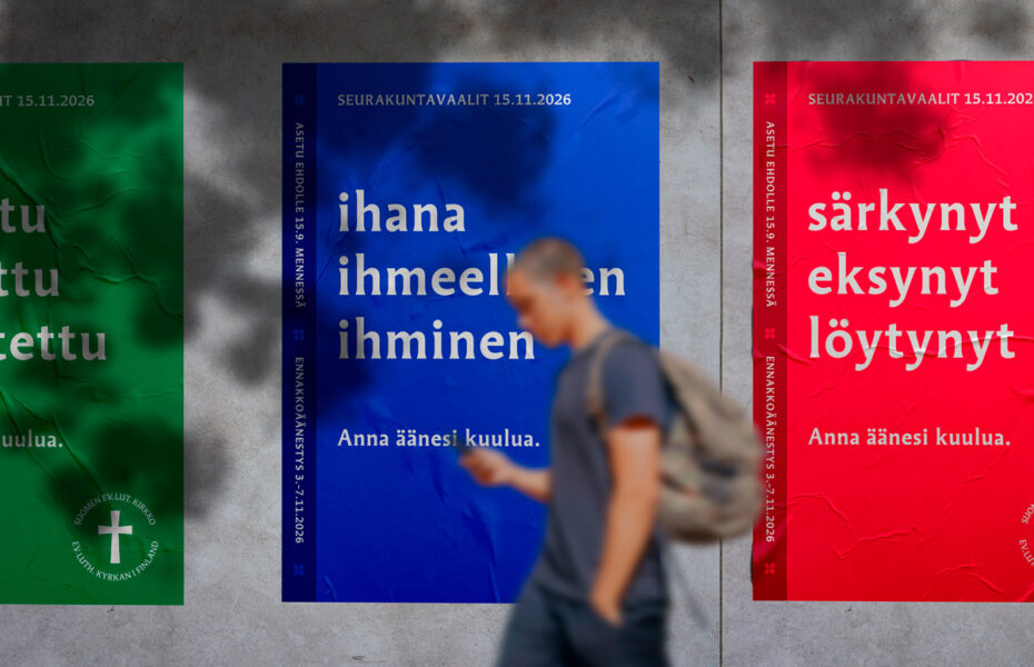 Kolme julistetta seinällä, ja mies kävelee ohi puhelin kädessään.