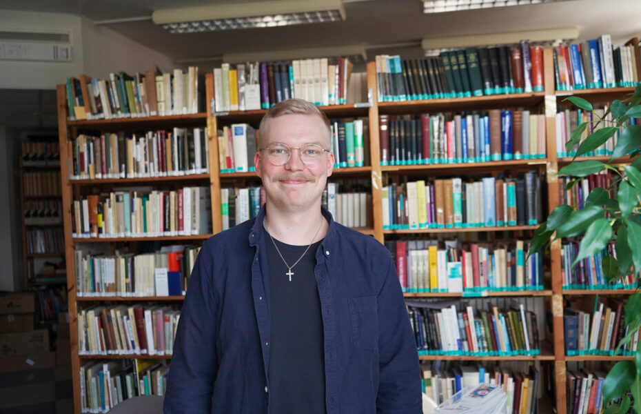 Kuvassa Konsta Järviluoma hymyilee kirjastossa.