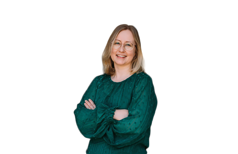 Nainen vihreässä paidassa hymyilee kädet puuskassa. Valkoinen tausta.