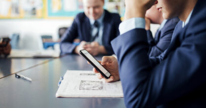 Poikia luokassa puhelin kädessä.