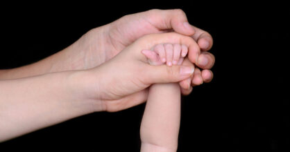 Äidin, isän ja vauvan kädet.