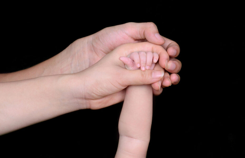 Äidin, isän ja vauvan kädet.