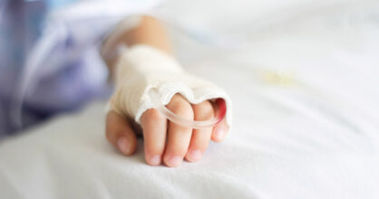 Lapsen käsi sairaalasängyllä. Kädessä on kanyyli.